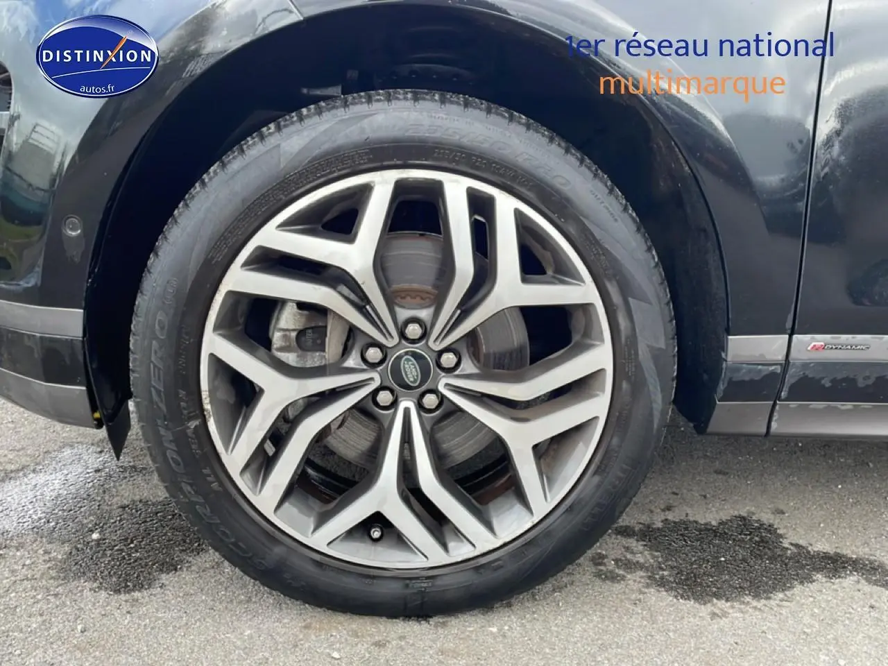 Gros plan sur la roue avant gauche du Range Rover Evoque noir avec jante alu et badge R-Dynamic visible.