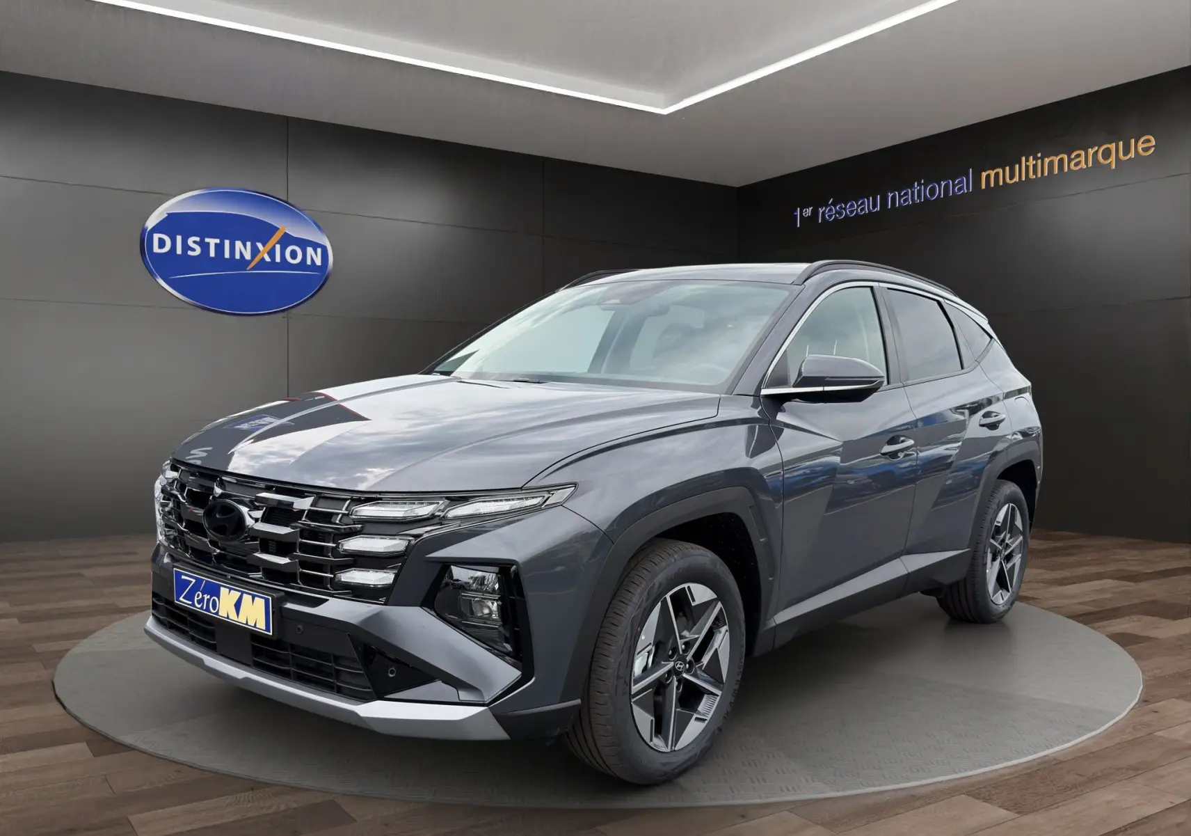 Hyundai Tucson 1.6 Hybrid gris foncé en 3/4 avant droit, avec calandre large et jantes alliage distinctives.
