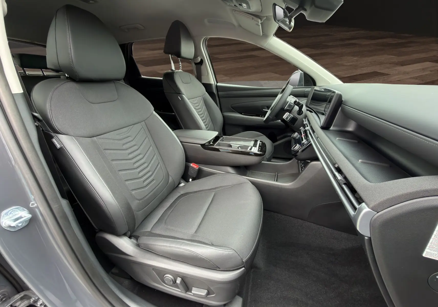 Intérieur avant droit du Hyundai Tucson 1.6 Hybrid 239 Creative 2026 en gris foncé, sièges tissu et tableau de bord moderne.