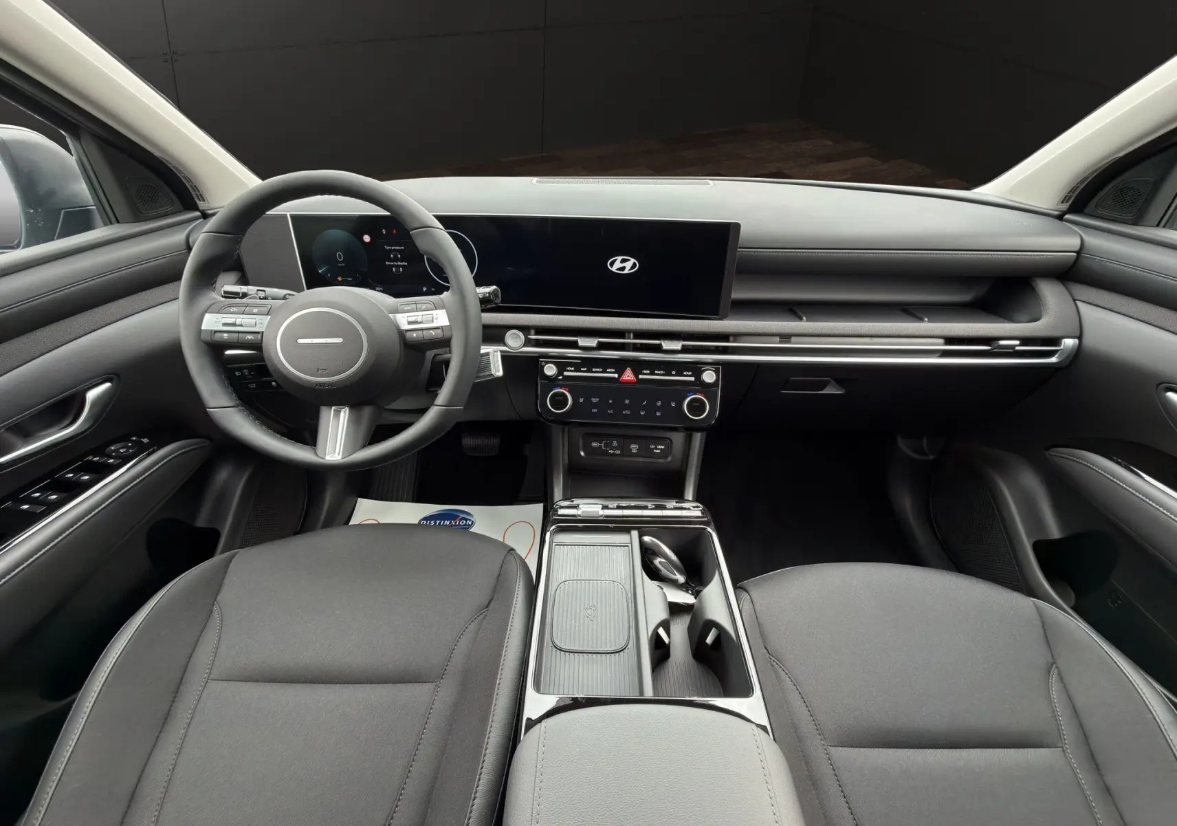 Vue intérieure avant du Hyundai Tucson 1.6 Hybrid gris foncé, avec tableau de bord digital et volant multifonctions cuir.