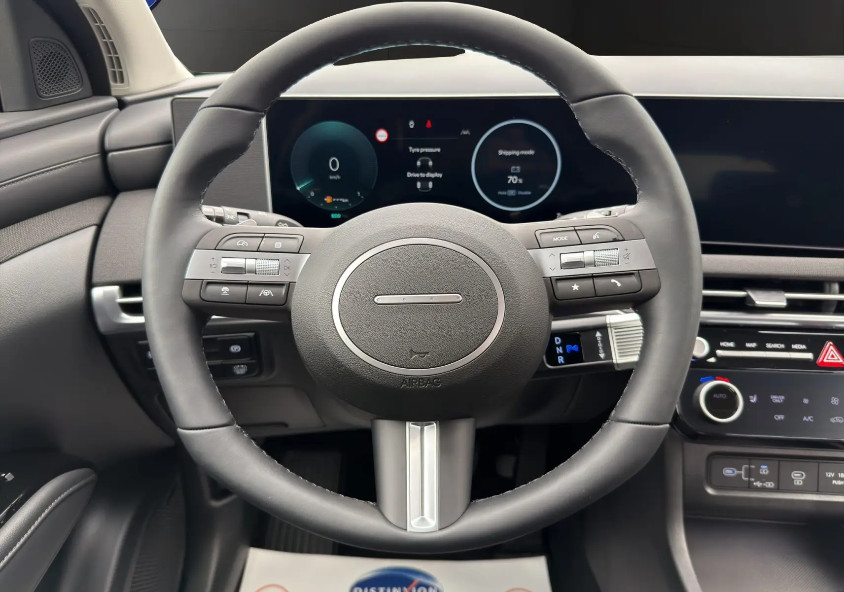 Vue frontale du volant cuir noir et du tableau de bord numérique du Hyundai Tucson 1.6 Hybrid 239 Creative Auto gris foncé.