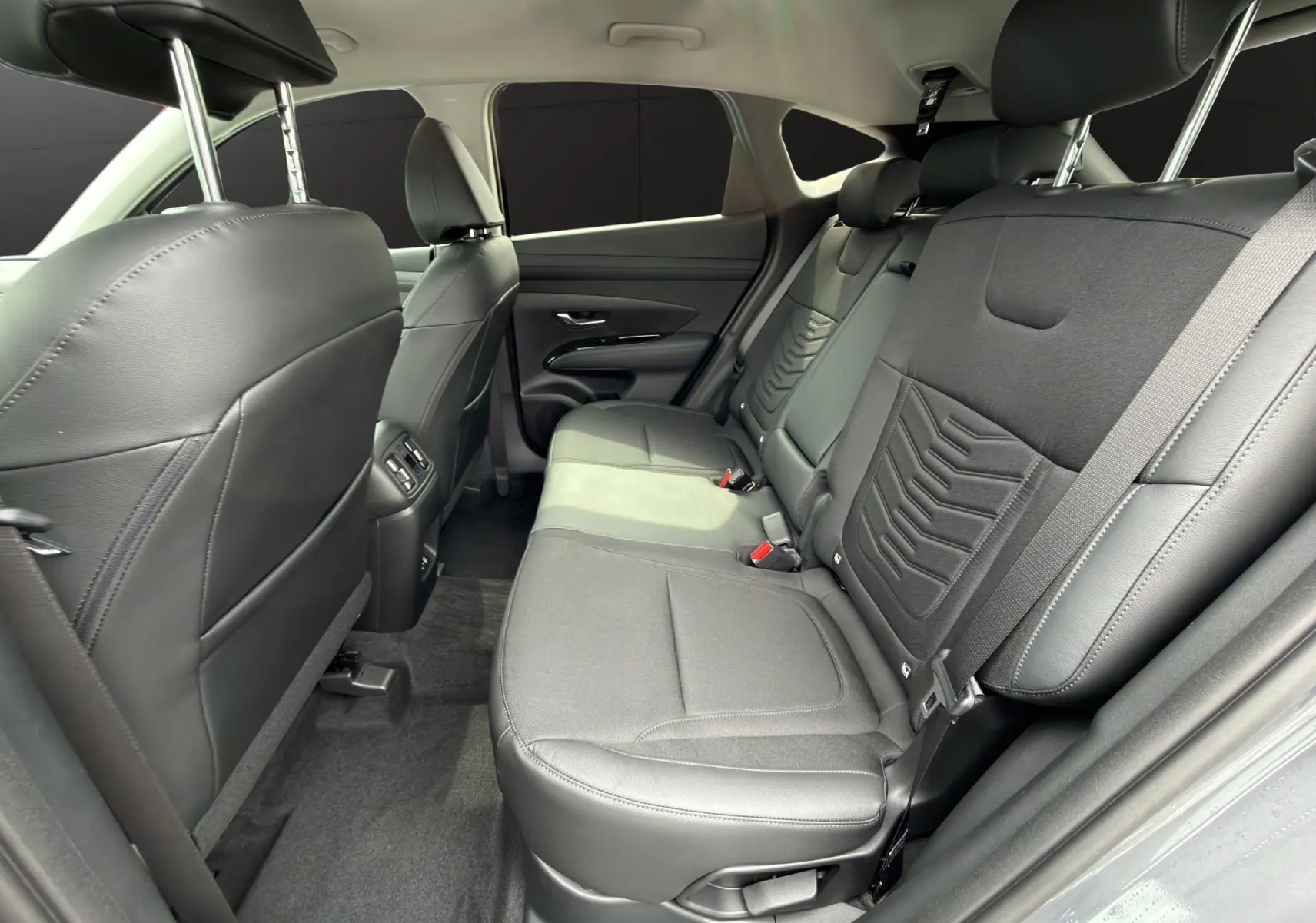 Vue intérieure arrière côté droit du Hyundai Tucson 1.6 Hybrid 239 Creative 2026 avec sièges noirs en tissu et cuir.