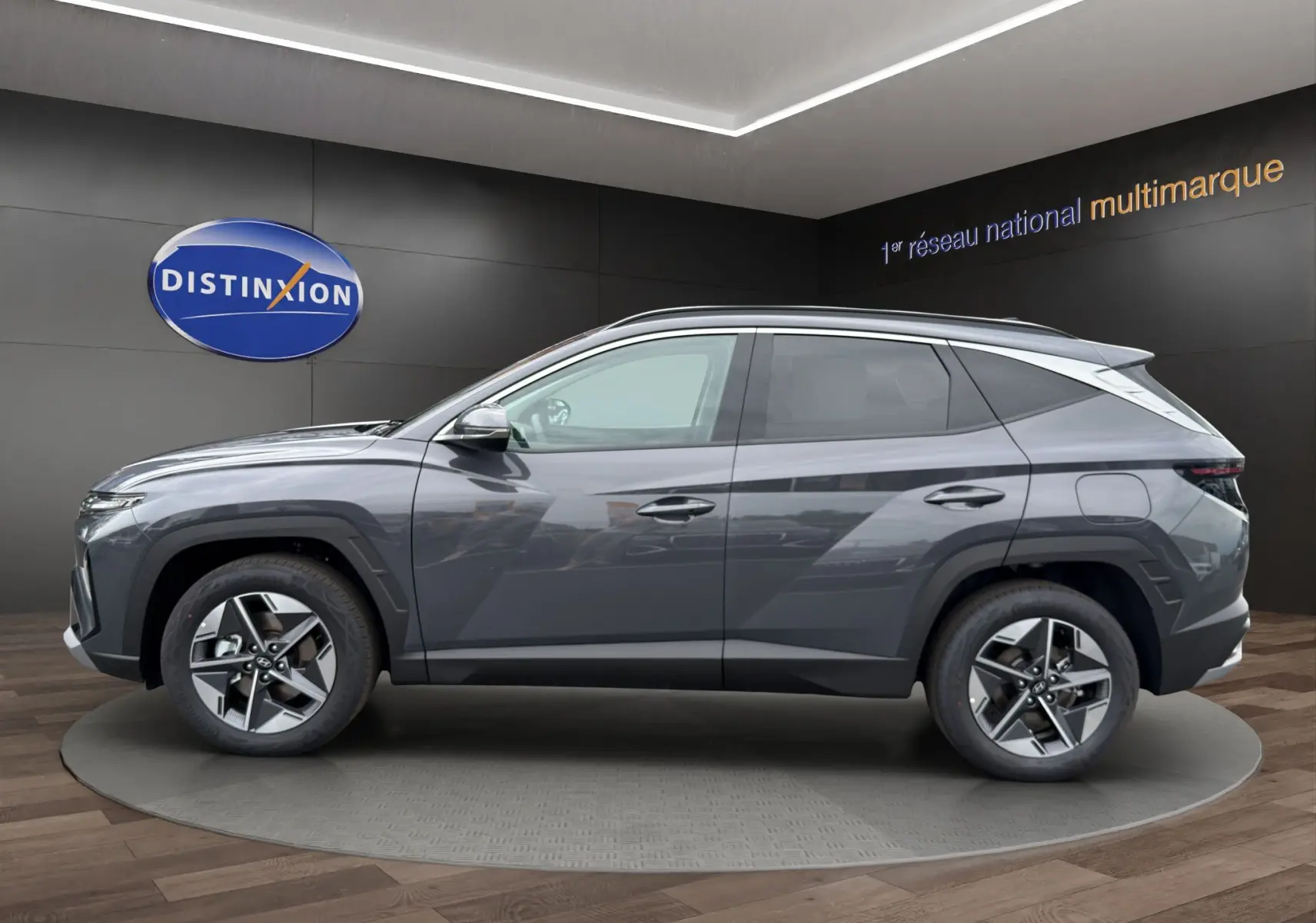 Vue de profil côté gauche du Hyundai Tucson 1.6 Hybrid gris foncé avec jantes alliage et lignes anguleuses marquées.