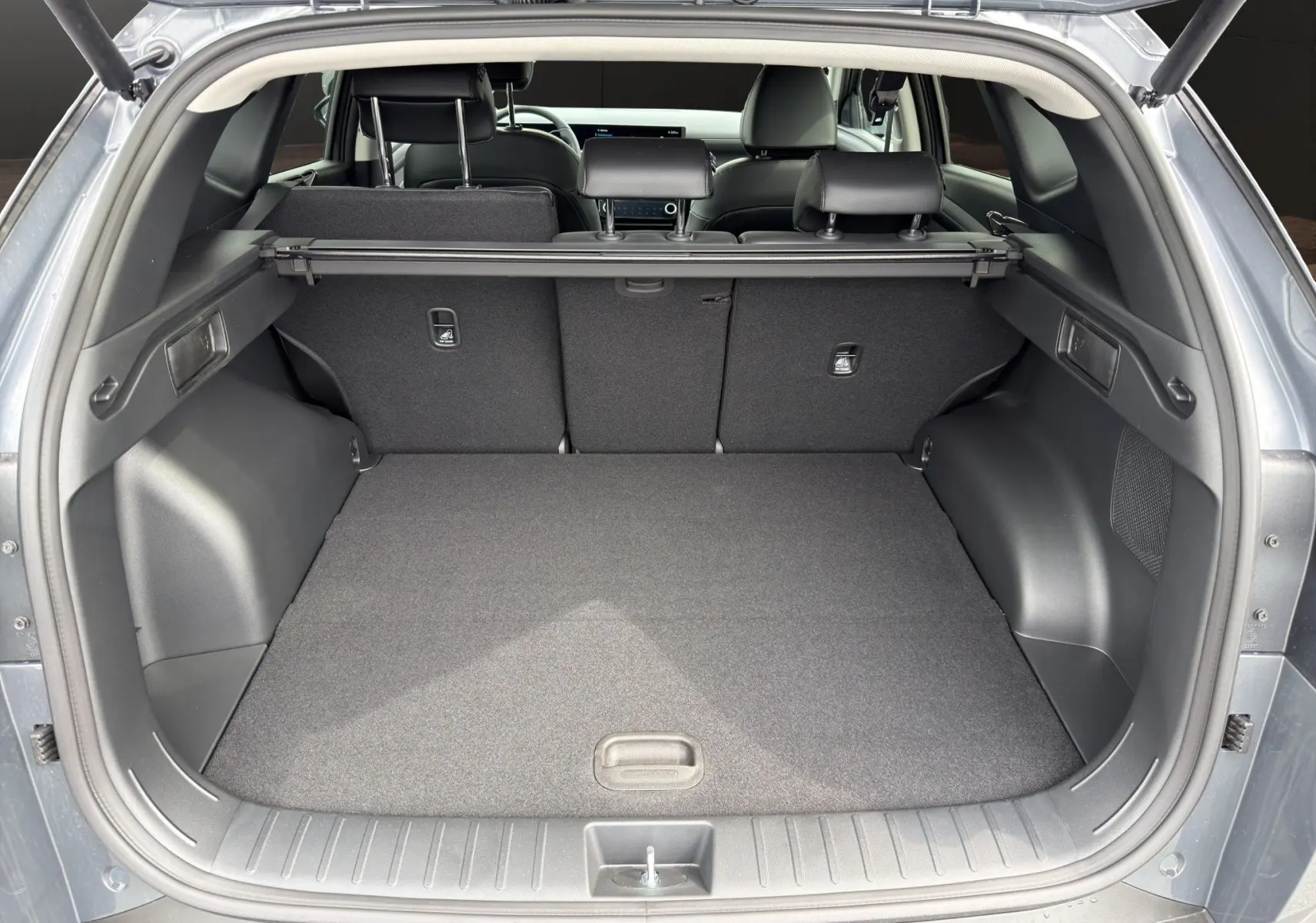 Coffre ouvert vu de l'arrière du Hyundai Tucson gris foncé 2026, avec banquette arrière et cache-bagages visibles.
