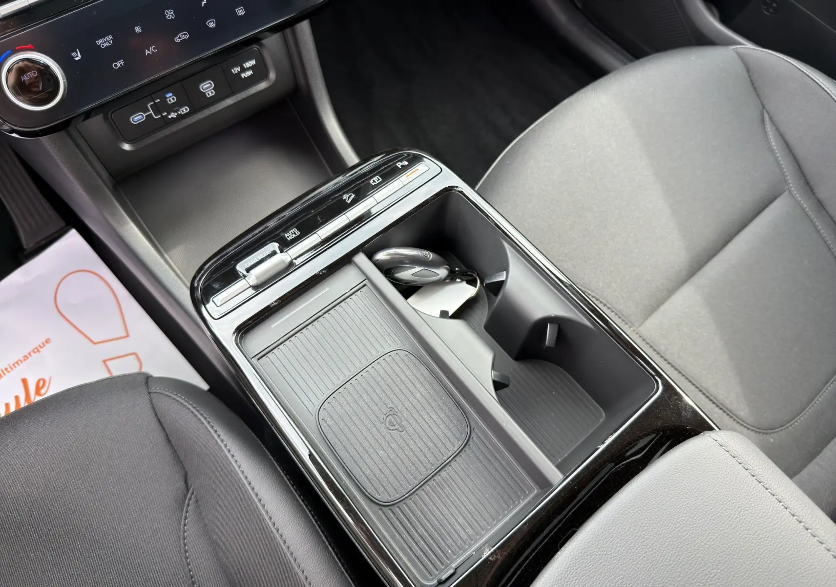 Vue rapprochée de la console centrale noire du Hyundai Tucson 1.6 Hybrid 239 Creative avec clé et rangements.