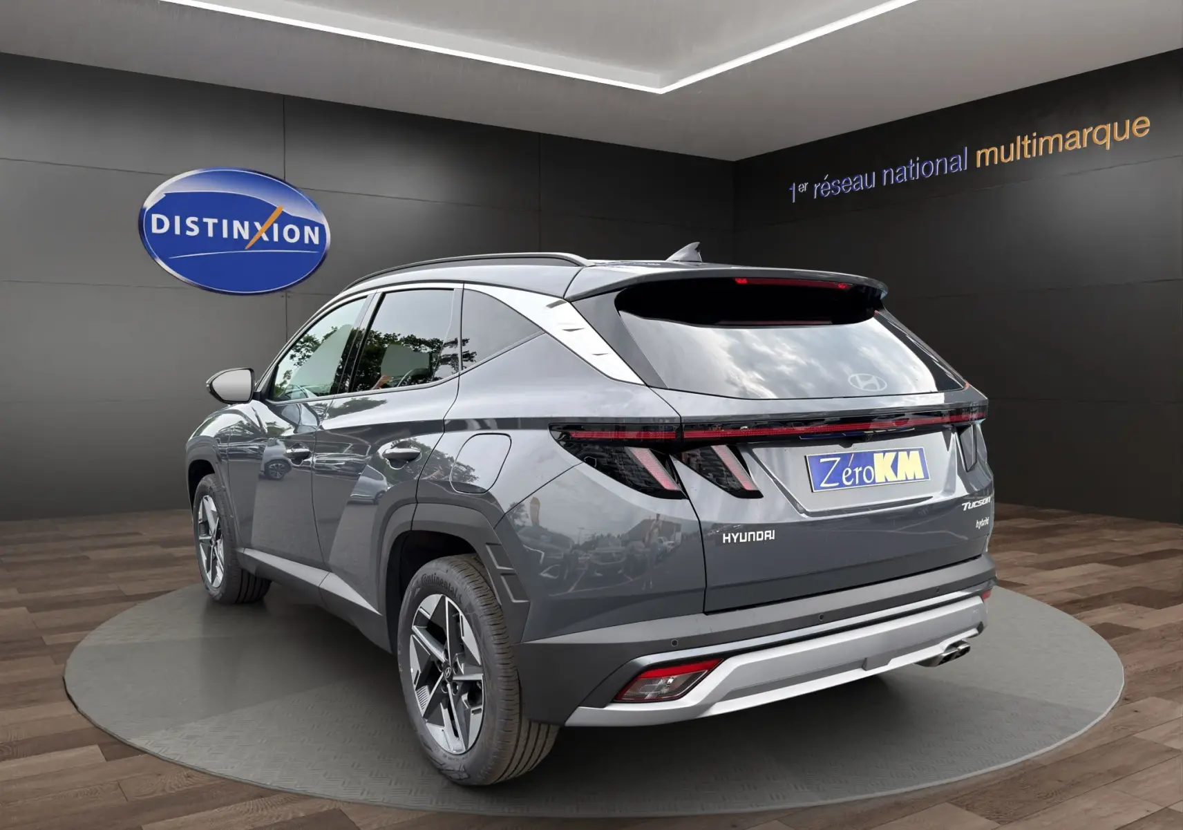 Vue 3/4 arrière d'un Hyundai Tucson gris foncé avec feux arrière LED et jantes alliage, en showroom.