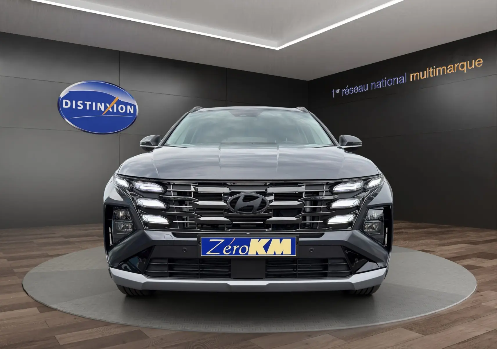 Vue frontale d'un Hyundai Tucson gris foncé avec calandre distinctive et éclairage LED intégré, en showroom.