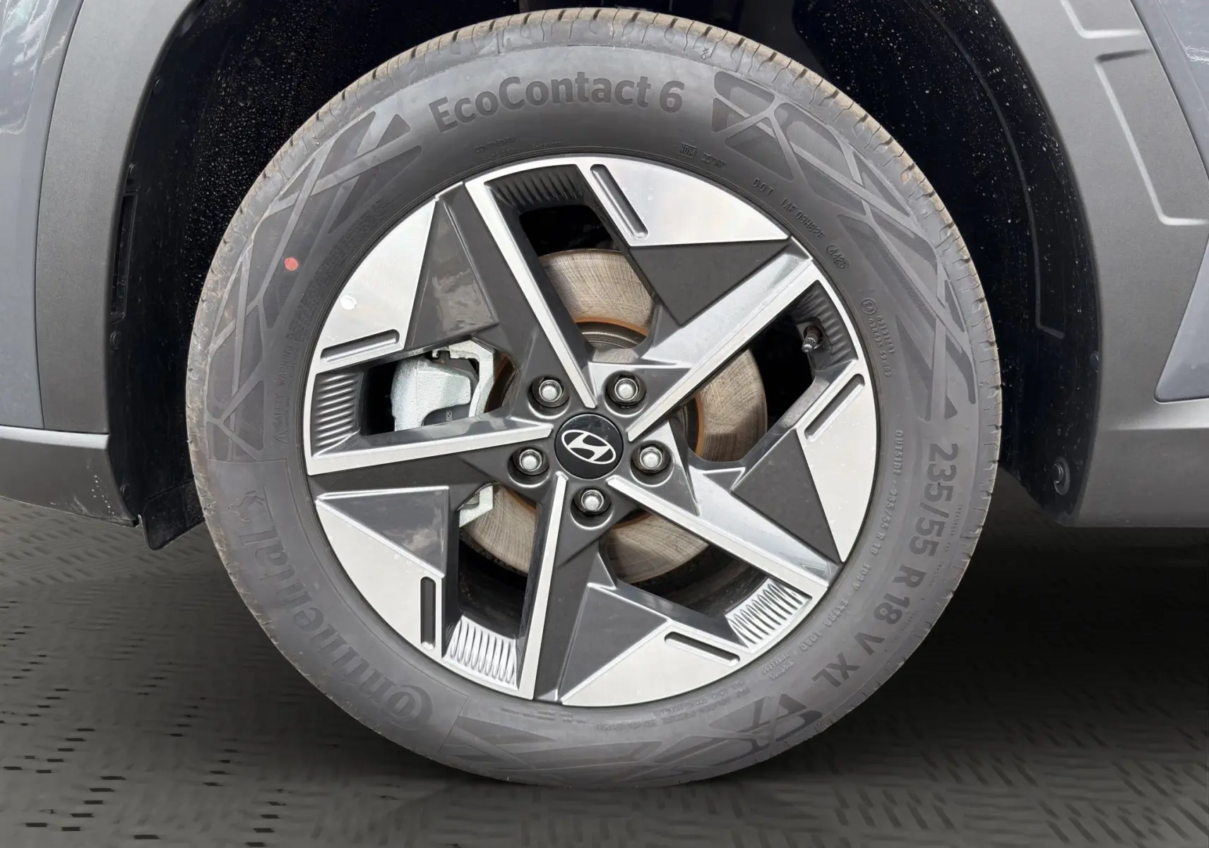Gros plan sur la roue avant gauche du Hyundai Tucson gris foncé, avec jante alliage à design géométrique moderne.