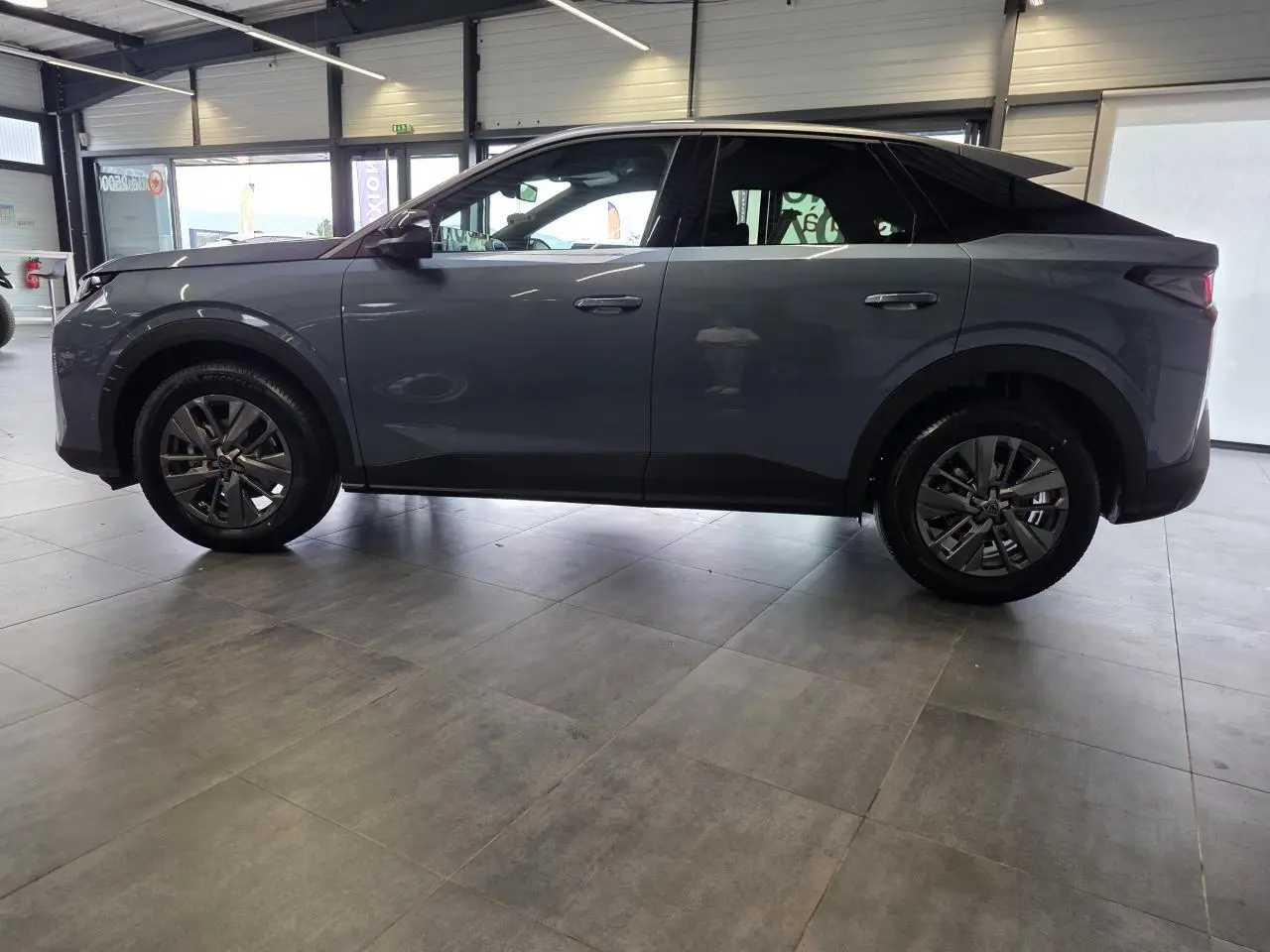Vue latérale gauche du Peugeot 3008 hybride 2026 bleu métallisé en intérieur, avec jantes alliage 18 pouces.