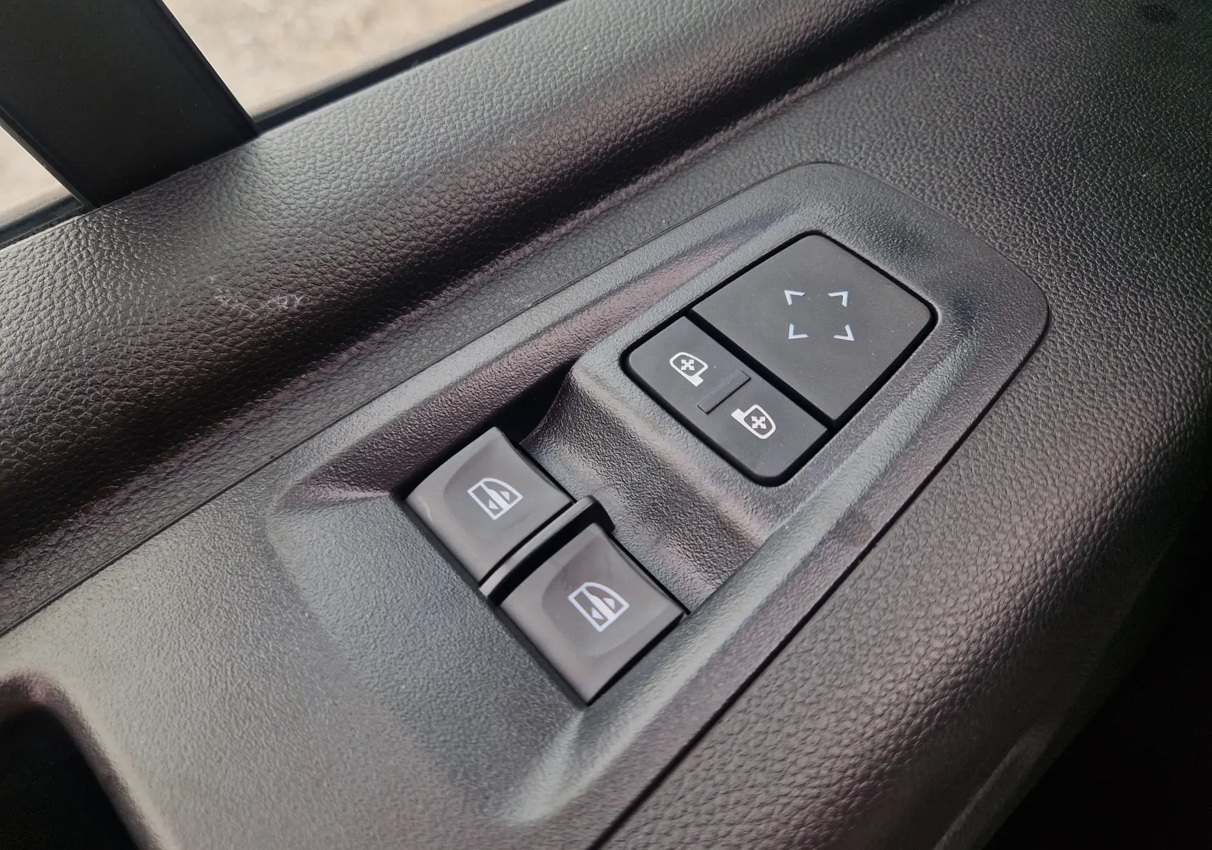 Gros plan sur les commandes de réglage des vitres et des rétroviseurs côté conducteur du Renault Master blanc 2026.