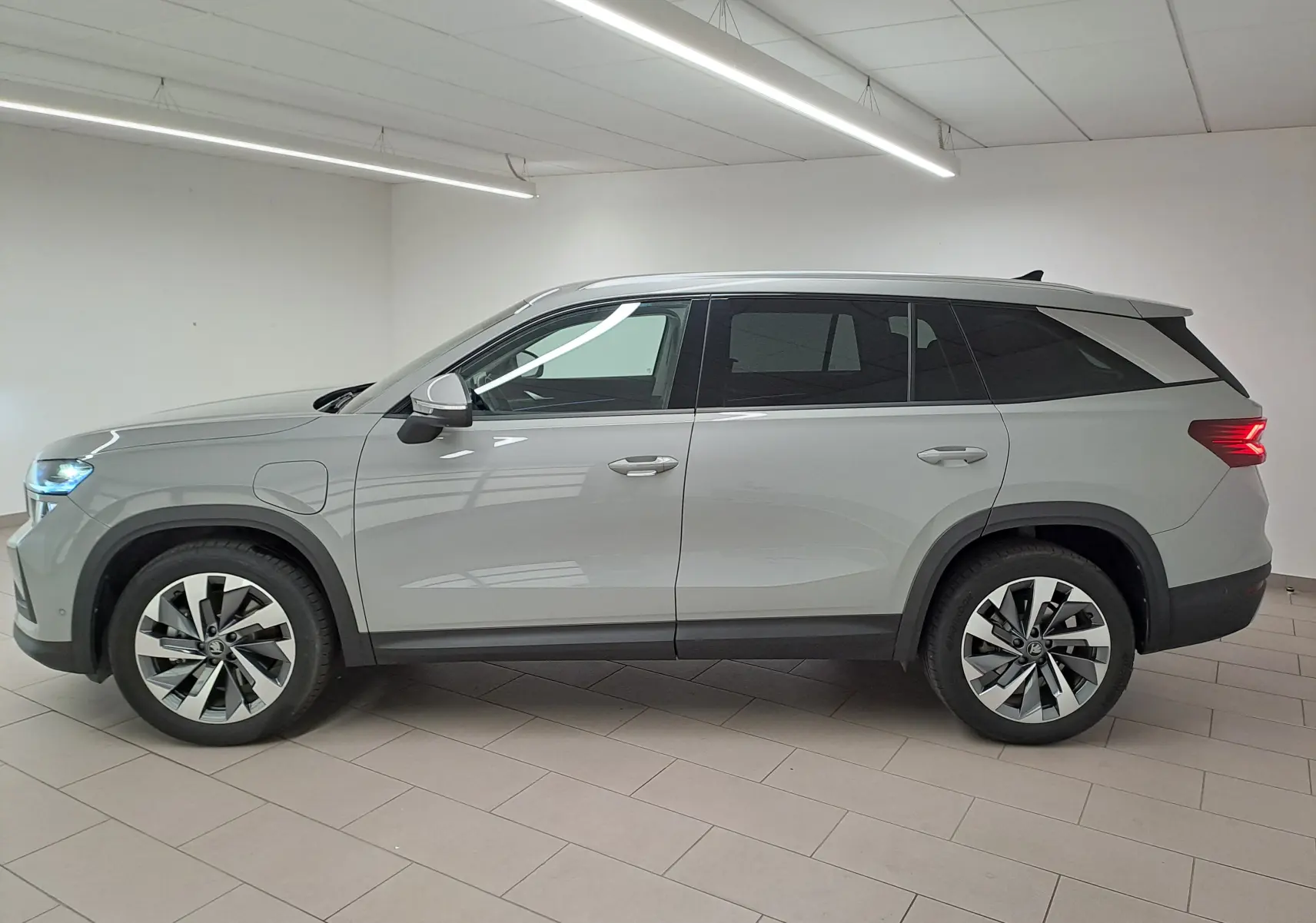 Vue latérale droite d'un Skoda Kodiaq gris perle 2025 avec jantes alliage 19'' et feux arrière allumés.