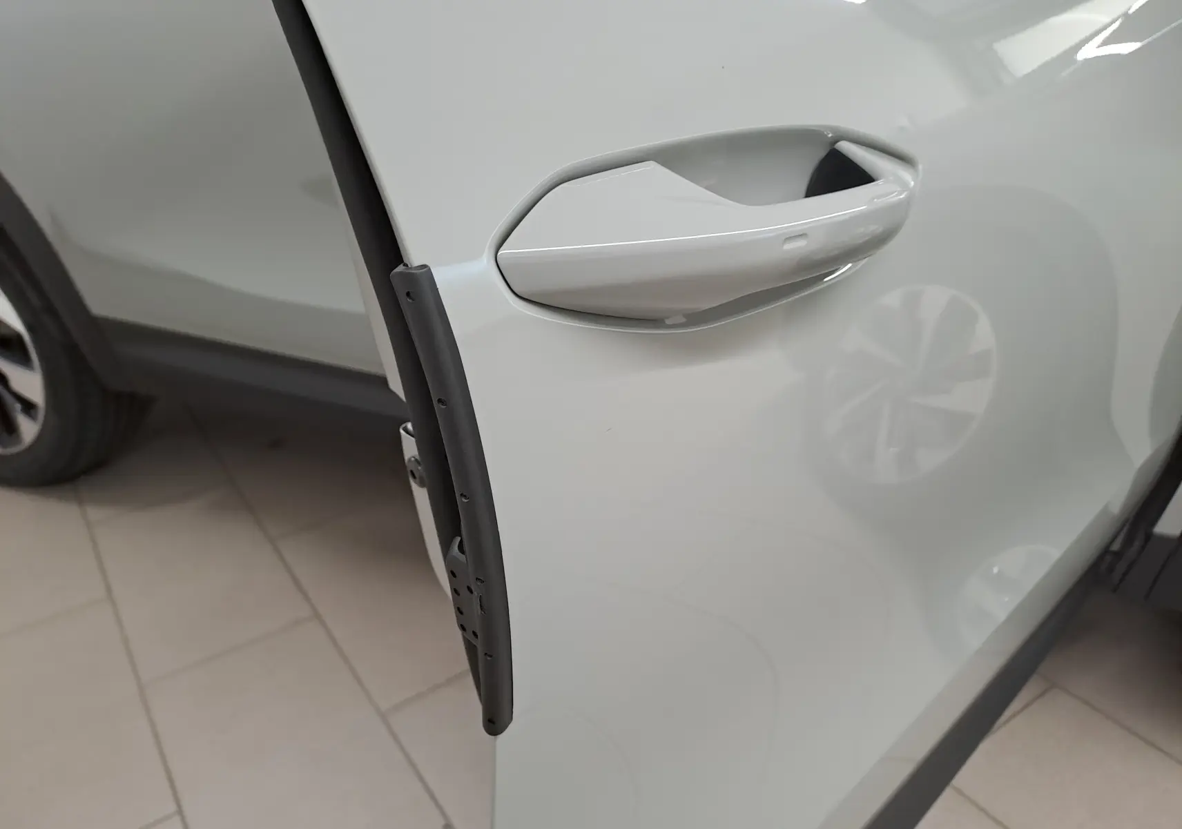 Gros plan sur la poignée de porte côté avant gauche du Skoda Kodiaq gris perle avec jante alliage visible en arrière-plan.