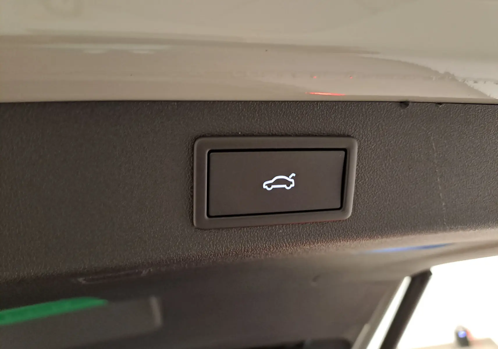 Bouton d'ouverture électrique du hayon sur le bord intérieur du coffre d'un Skoda Kodiaq gris perle.