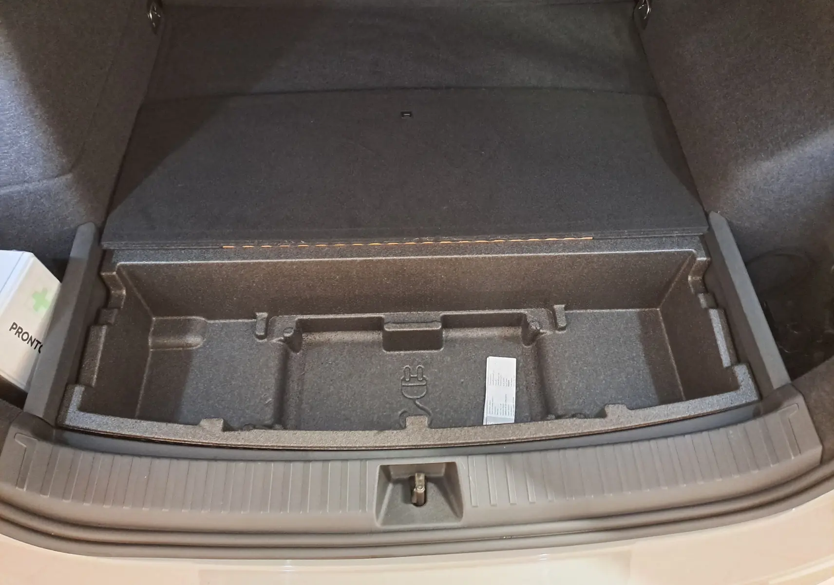 Coffre ouvert vu de dessus du Skoda Kodiaq gris perle, montrant le rangement sous plancher et une trousse de secours.