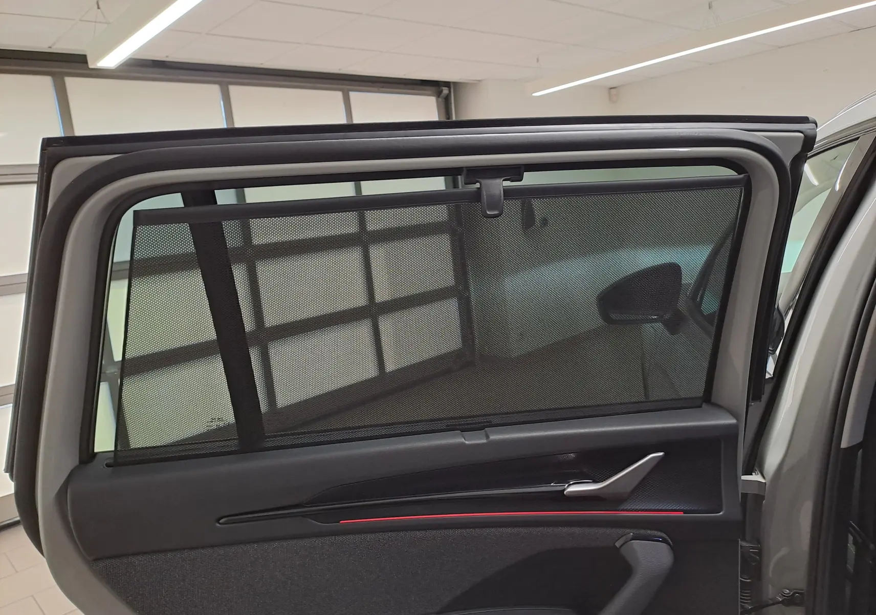 Vue intérieure de la porte arrière droite d’un Skoda Kodiaq gris perle avec pare-soleil intégré et garniture noire.