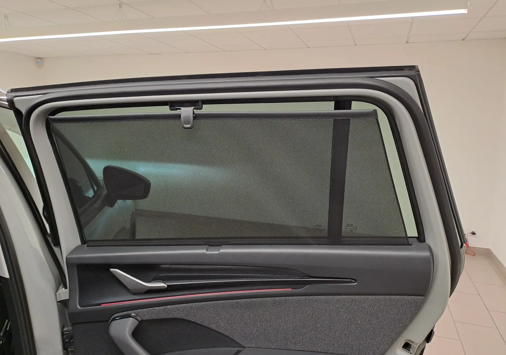 Vue intérieure de la porte arrière gauche d'un Skoda Kodiaq gris perle avec pare-soleil intégré et poignée argentée.