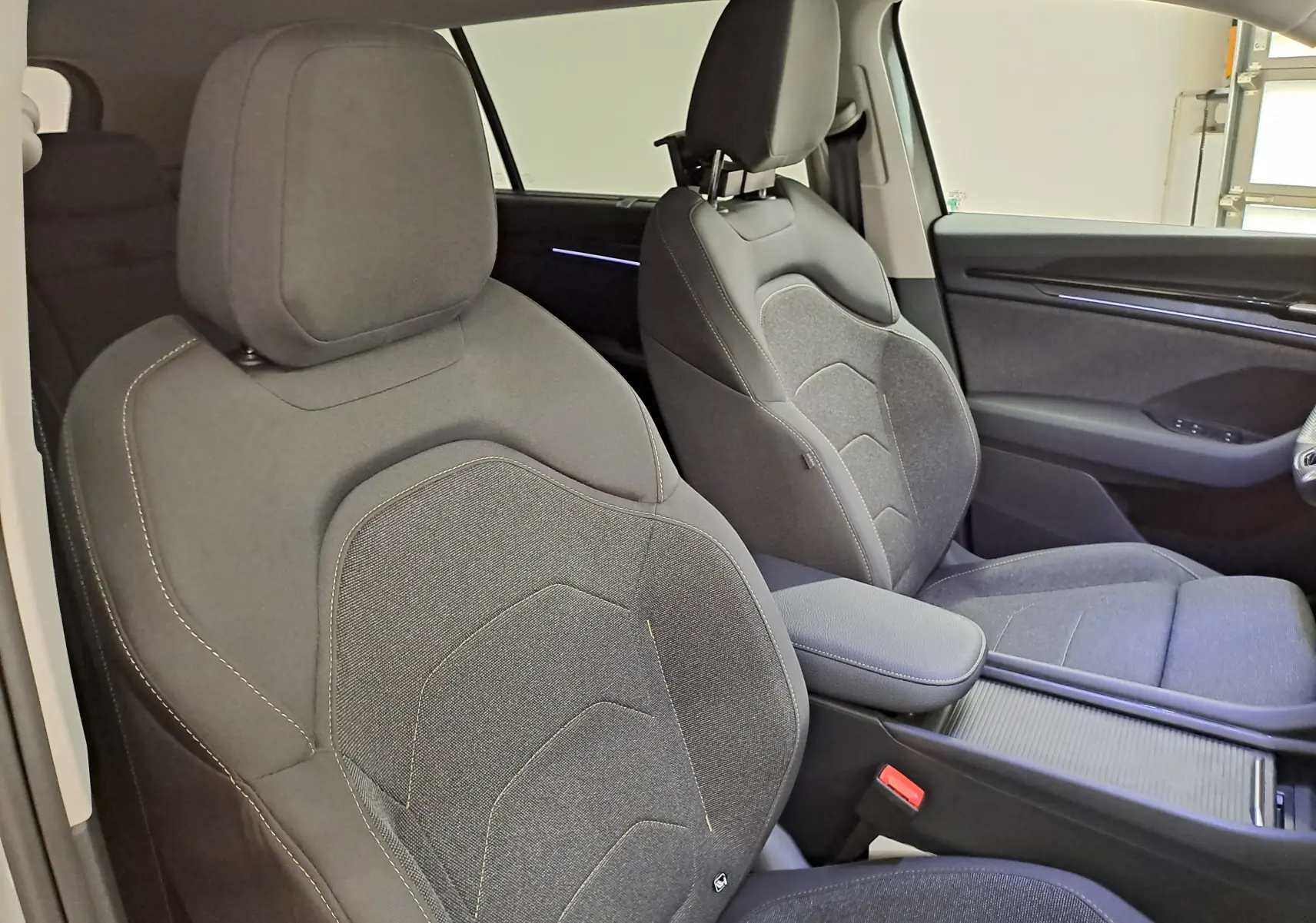 Vue intérieure côté avant droit du Skoda Kodiaq 2025, sièges tissu gris foncé avec surpiqûres claires.