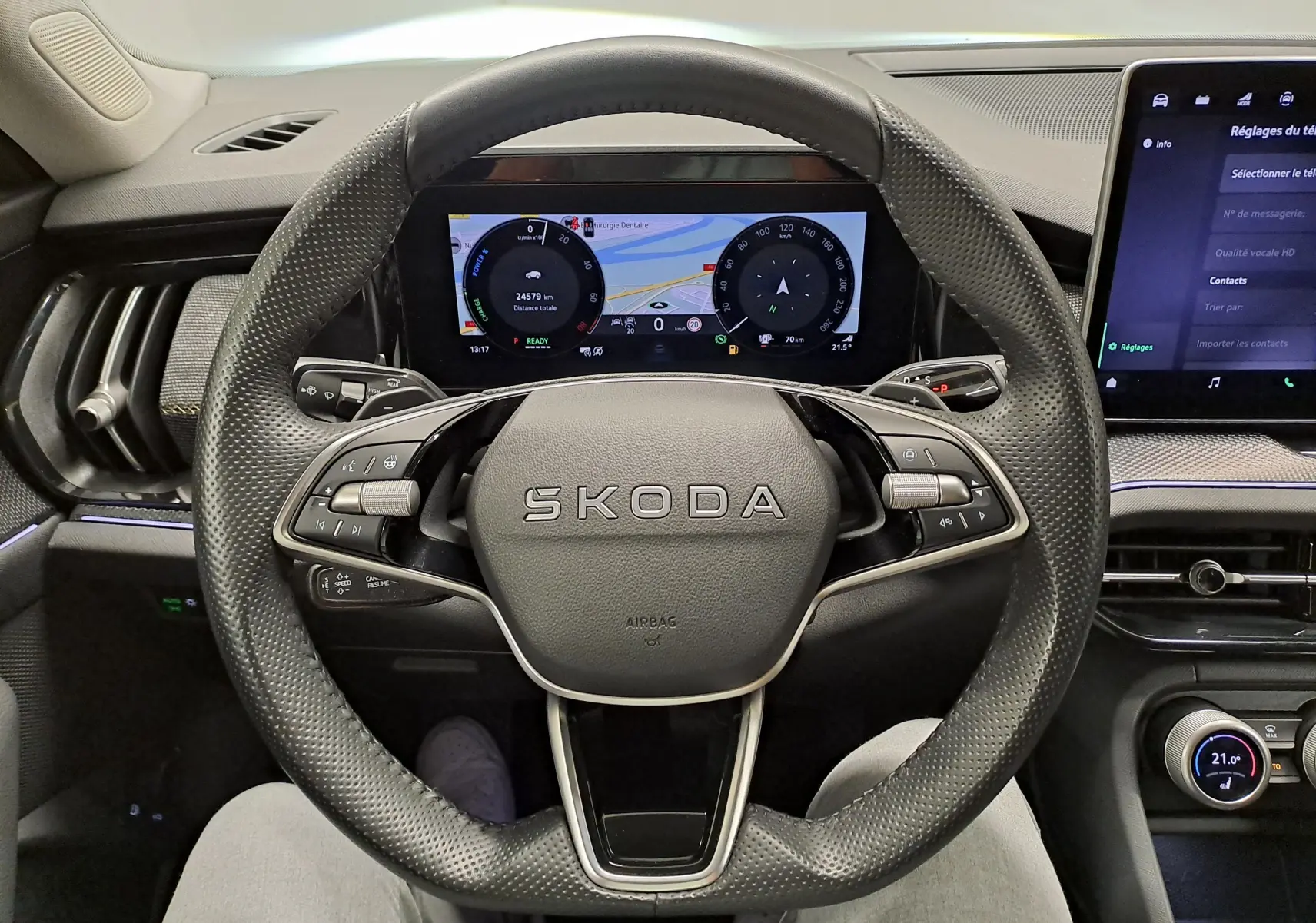 Vue intérieure centrée sur le volant perforé SKODA d'un KODIAQ 2025 avec tableau de bord numérique et écran tactile.