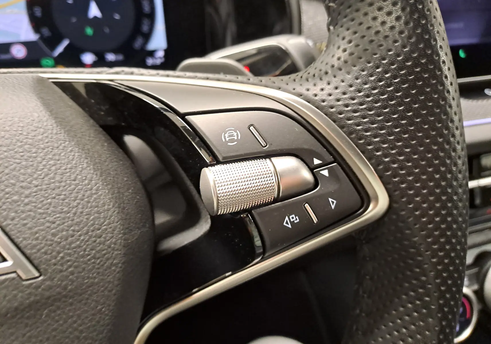 Gros plan sur les commandes multifonctions en métal et cuir perforé du volant d’un Skoda Kodiaq gris perle 2025.
