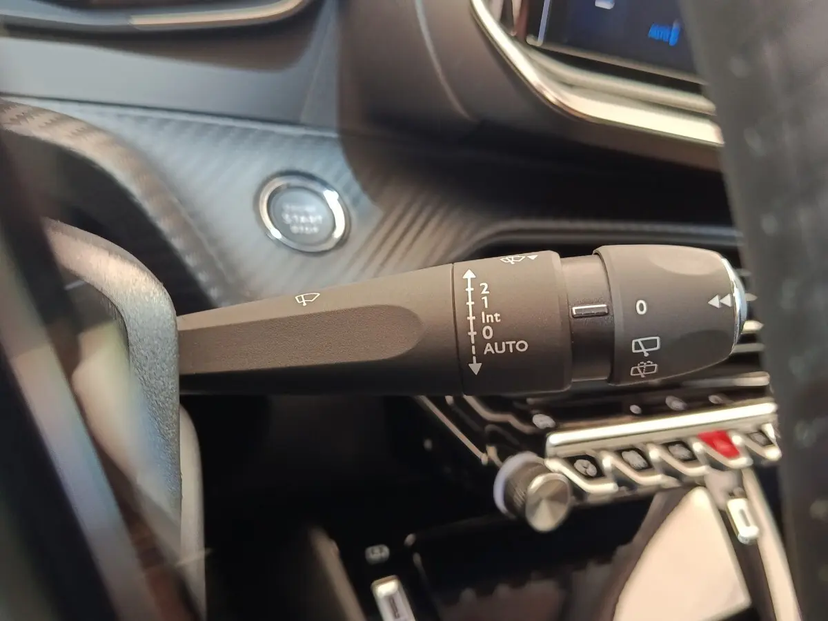 Gros plan sur la commande d’essuie-glace côté droit du tableau de bord d’une Peugeot 208 électrique blanche 2024.