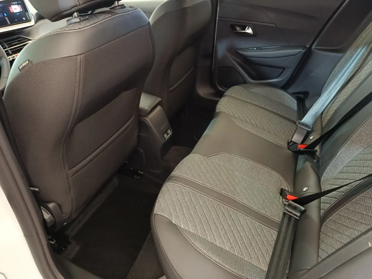 Vue intérieure arrière côté droit de la banquette grise et noire de la Peugeot 208 électrique 2024, avec ceintures de sécurité visibles.