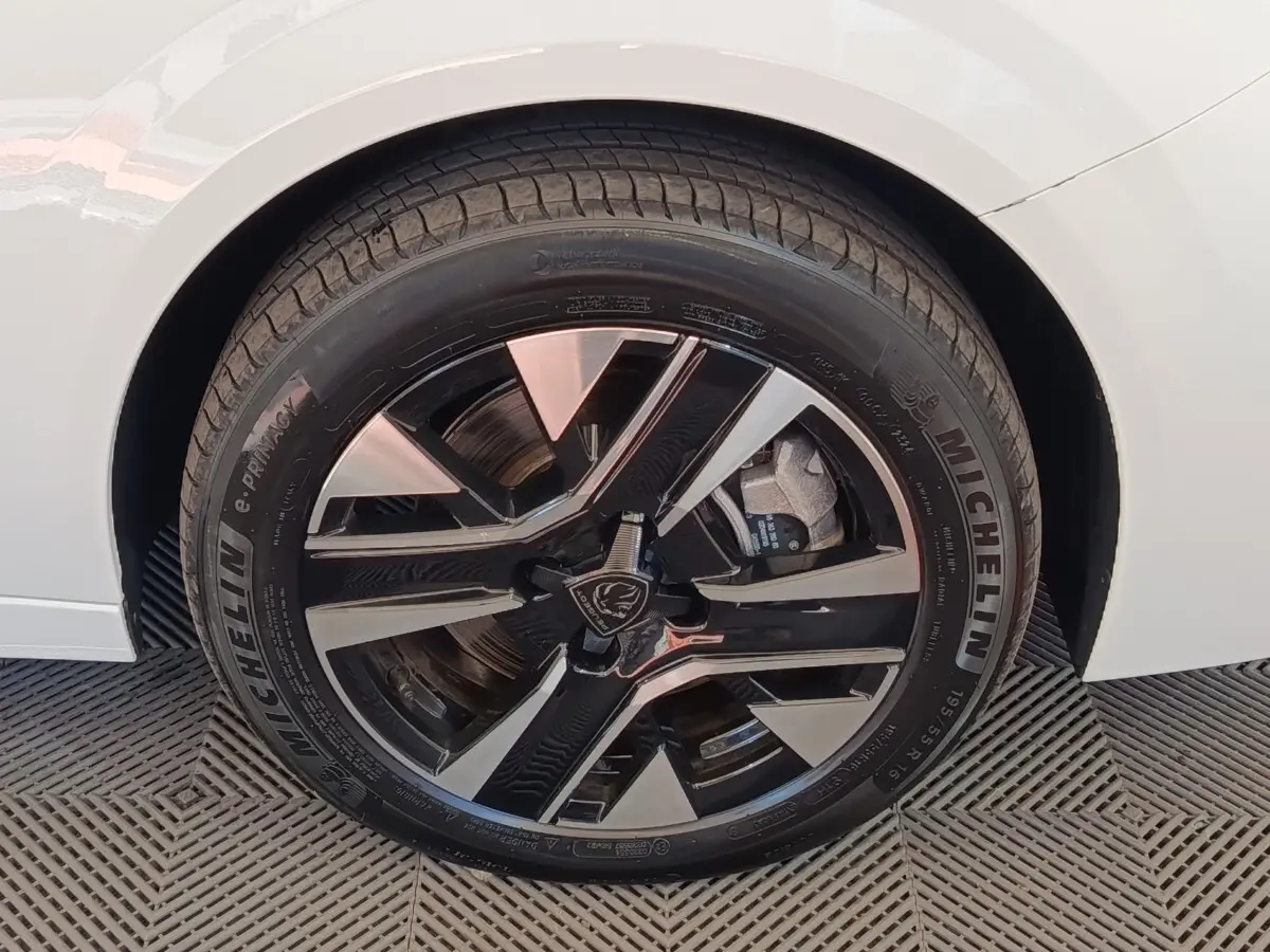 Gros plan sur la roue avant droite d’une Peugeot 208 électrique blanche avec jante alliage noire et argent.