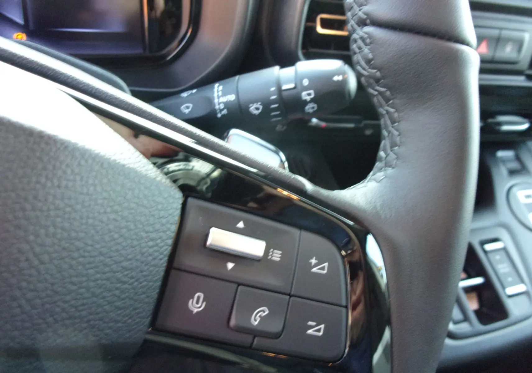 Gros plan sur les commandes au volant en cuir noir du Citroën Berlingo 2025, version diesel gris Artense.