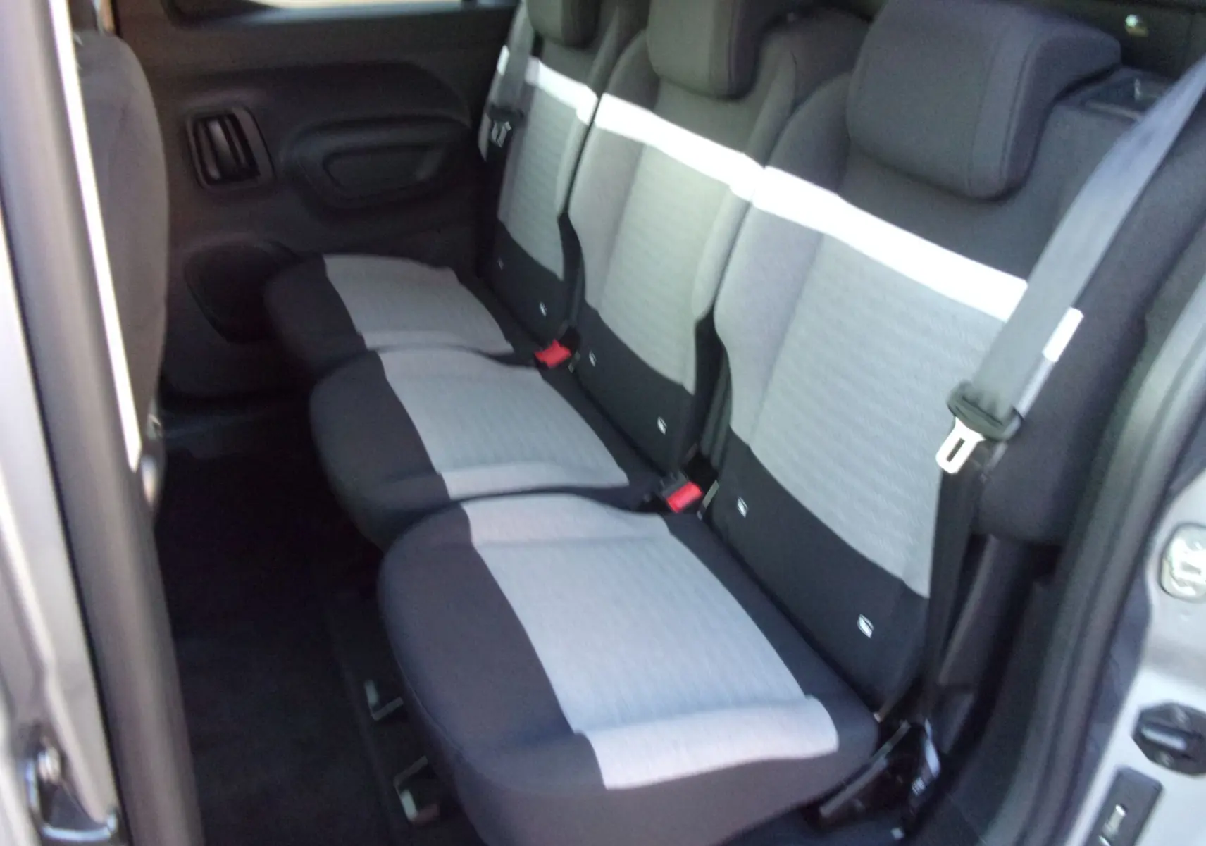 Vue intérieure des sièges arrière gris clair et noir du Citroën Berlingo 2025, version diesel, porte ouverte côté droit.