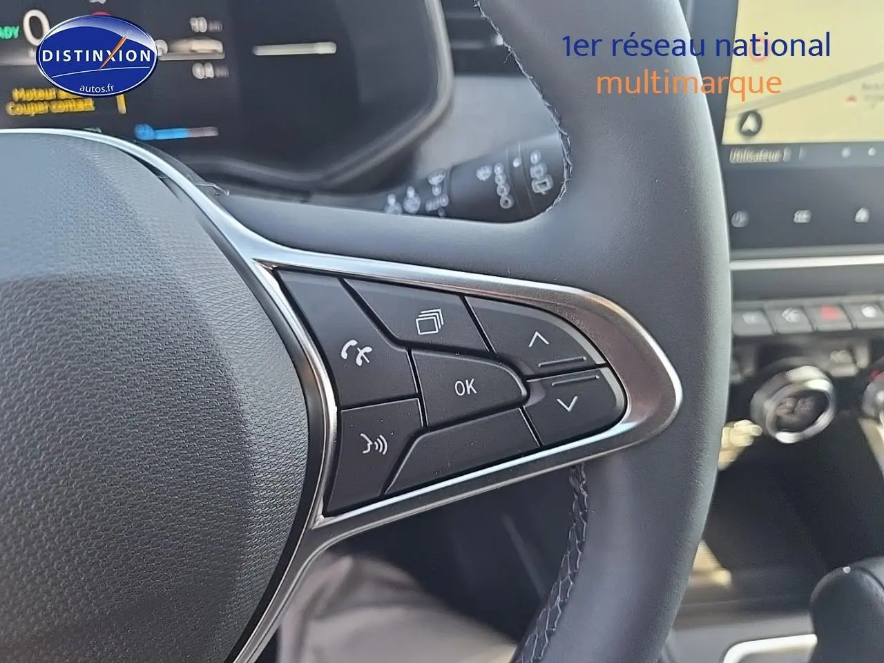 Gros plan sur les commandes multifonctions du volant côté droit de la Renault Clio V, intérieur moderne et écran tactile visible.