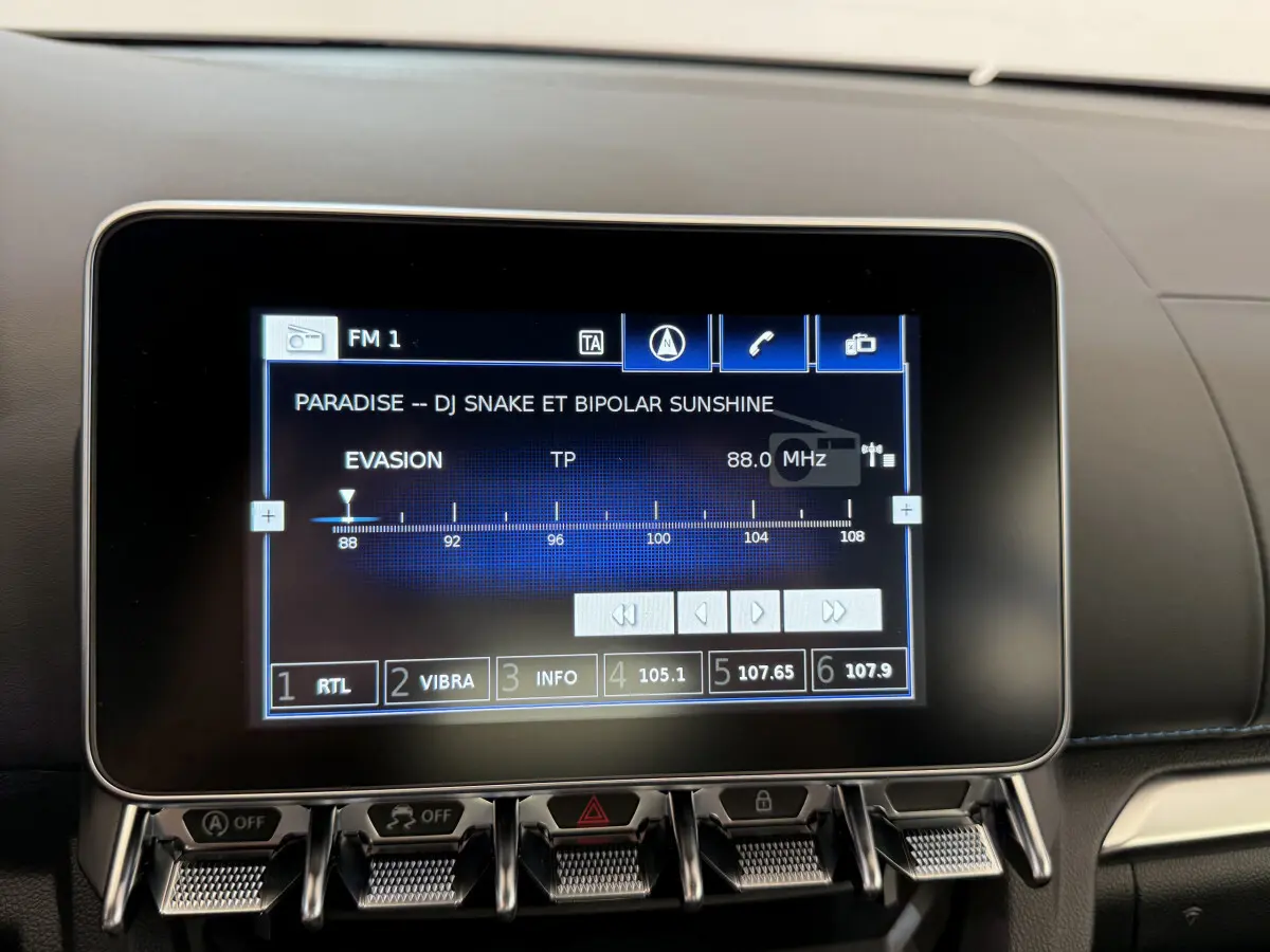 Écran tactile central affichant la radio dans l'habitacle de l'Alpine A110 Legende bleu, vue rapprochée.