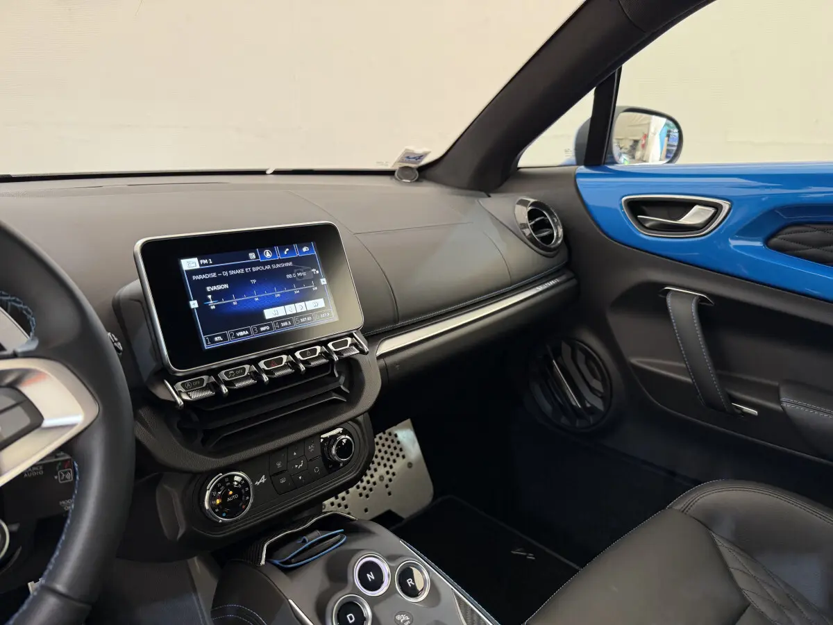Intérieur côté passager de l'Alpine A110 Légende 2019 bleu, avec écran tactile central et finitions cuir noires.