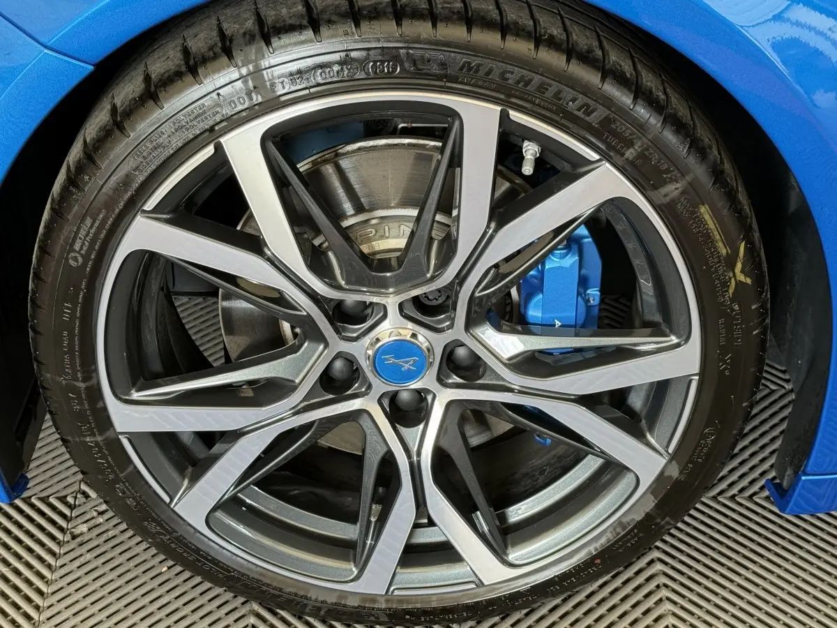 Gros plan sur la jante alliage à dix branches de l'ALPINE A110 Legende bleue avec étrier de frein bleu visible.