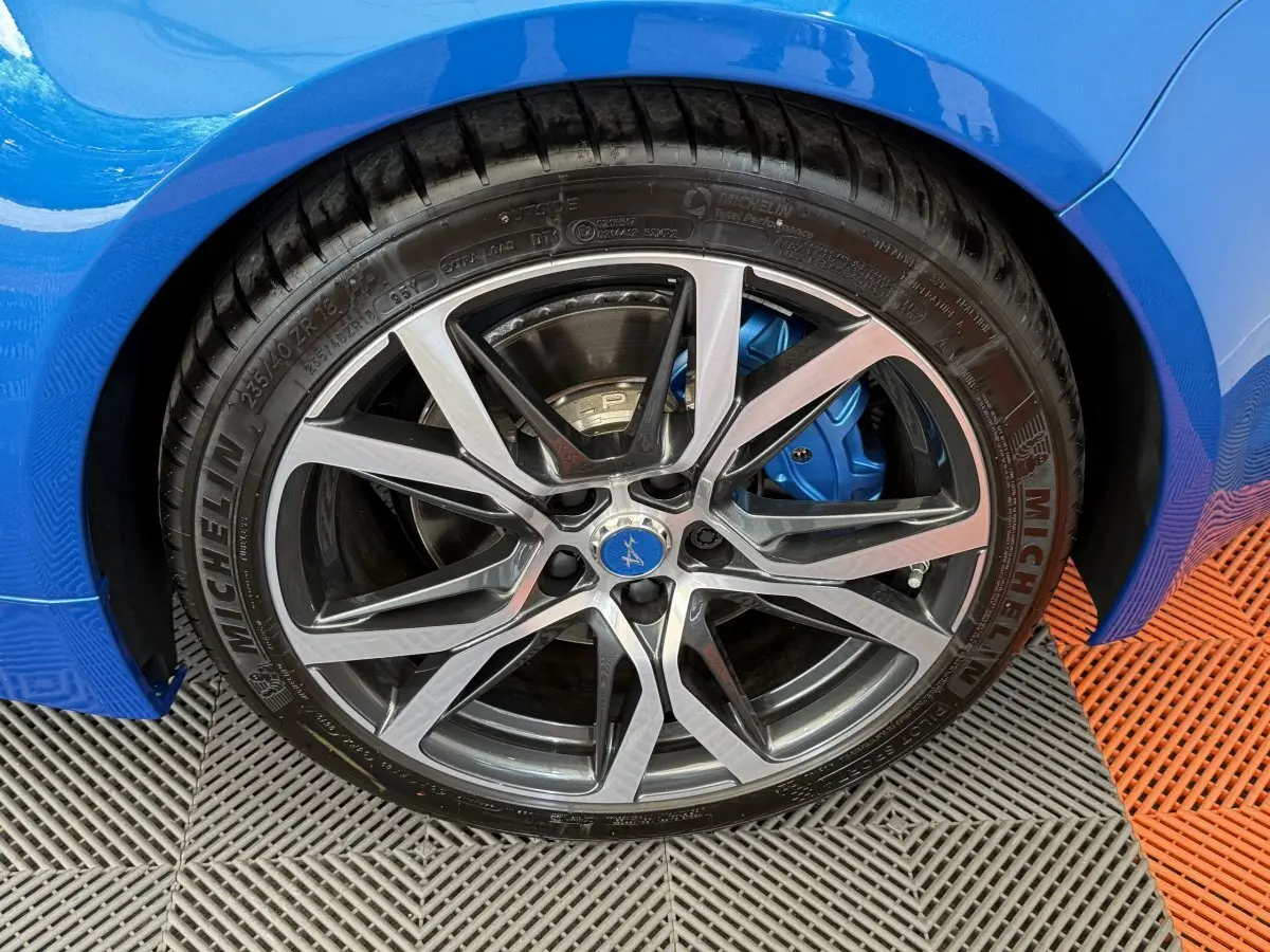 Gros plan sur la roue avant droite d'une Alpine A110 Legende bleu, avec étrier de frein bleu visible.