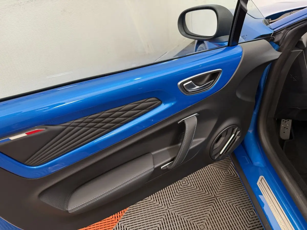 Détail de la porte côté conducteur bleu de l'Alpine A110 Légende 2019 avec surpiqûres et poignée en cuir.