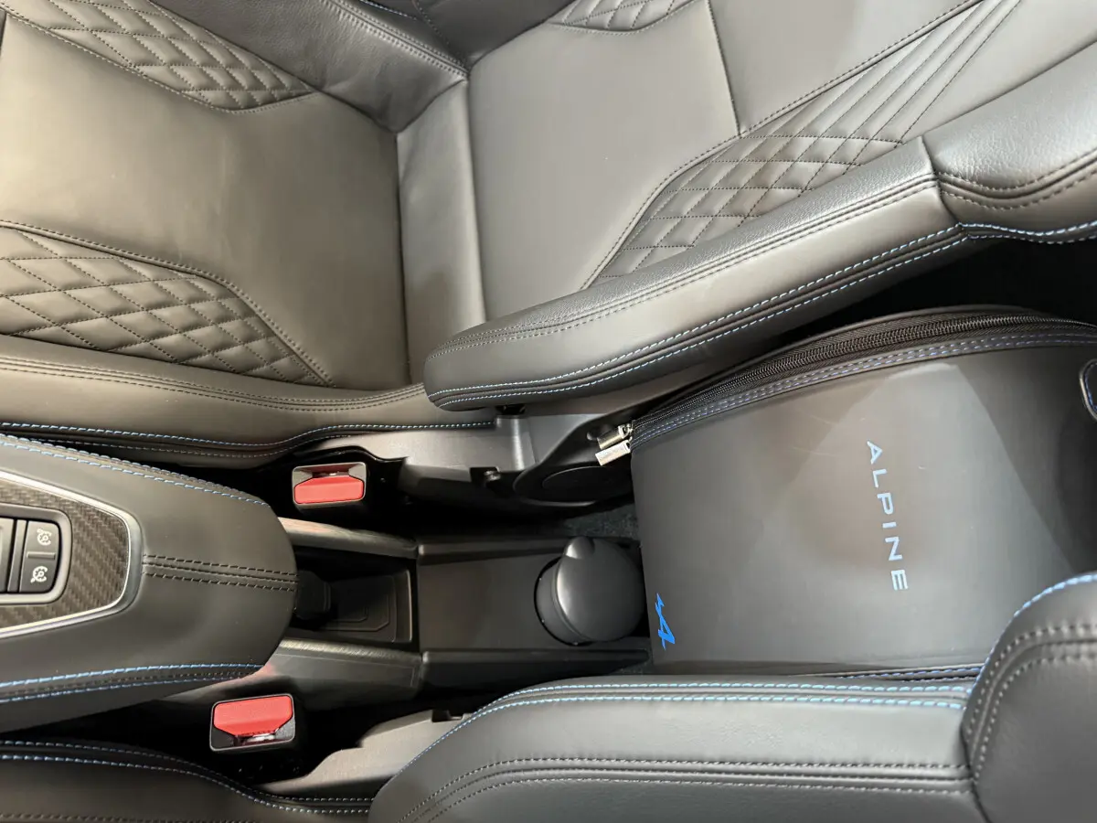 Vue rapprochée de l'intérieur noir avec surpiqûres bleues et sac Alpine entre les sièges de l'Alpine A110 Legende.