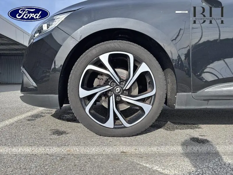 Gros plan sur la roue avant gauche noire étoilée du Renault Grand Scenic 2017 avec jante diamantée et logo Renault visible.