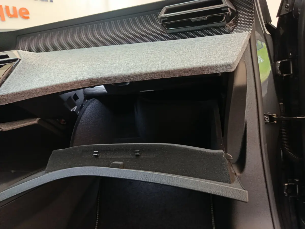 Vue intérieure sur la boîte à gants ouverte du Peugeot 3008 blanc, montrant le revêtement textile gris clair du tableau de bord.