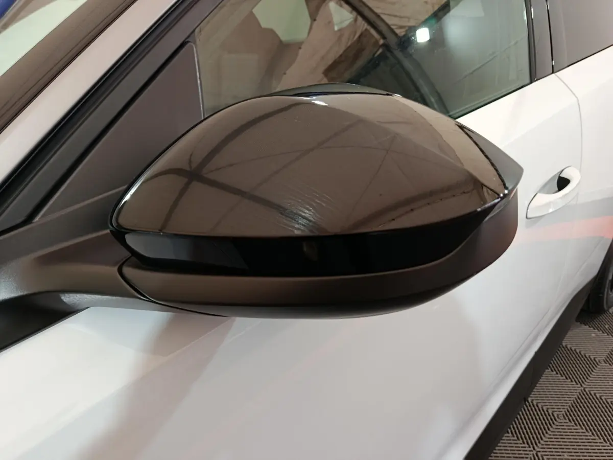 Gros plan sur le rétroviseur noir côté gauche du Peugeot 3008 blanc, avec portière et poignée visibles.