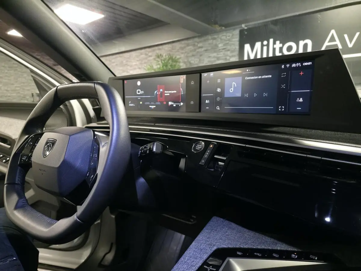 Vue intérieure du tableau de bord du Peugeot 5008 blanc 2025, avec volant compact et double écran HD panoramique.