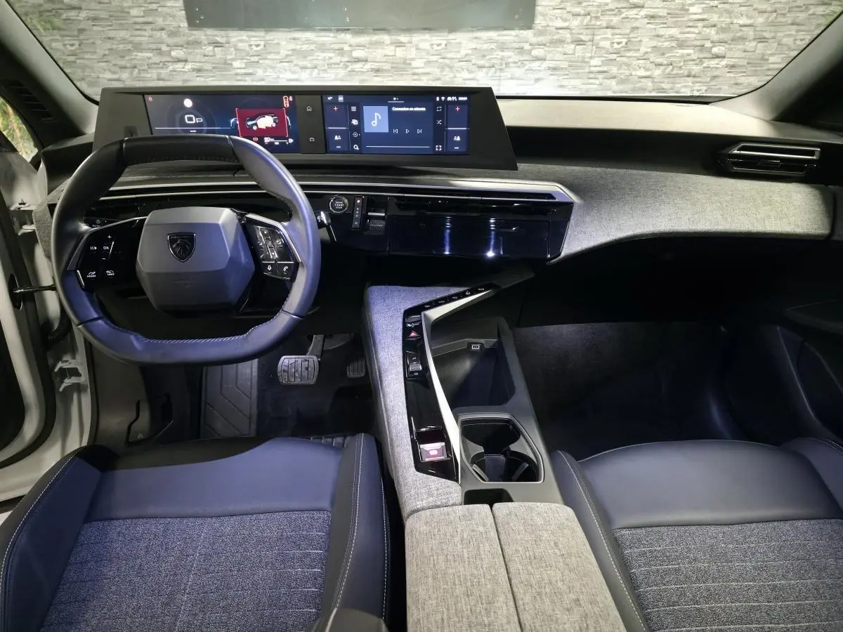 Vue intérieure avant du Peugeot 5008 2025, tableau de bord avec double écran HD et volant compact cuir noir.