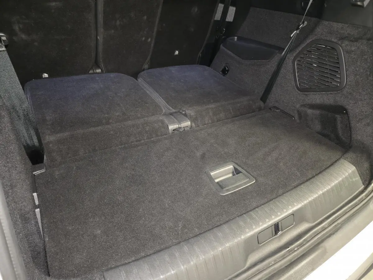 Vue rapprochée du coffre du Peugeot 5008 blanc 2025 avec banquette arrière rabattue et revêtement noir.