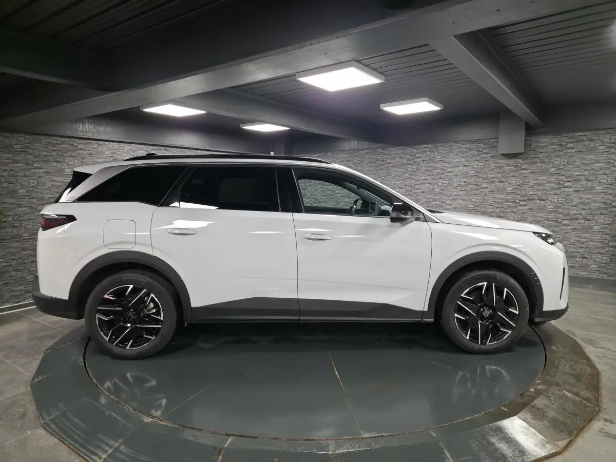 Peugeot 5008 blanc vue de profil côté gauche, avec jantes alliage noires et toit noir brillant.
