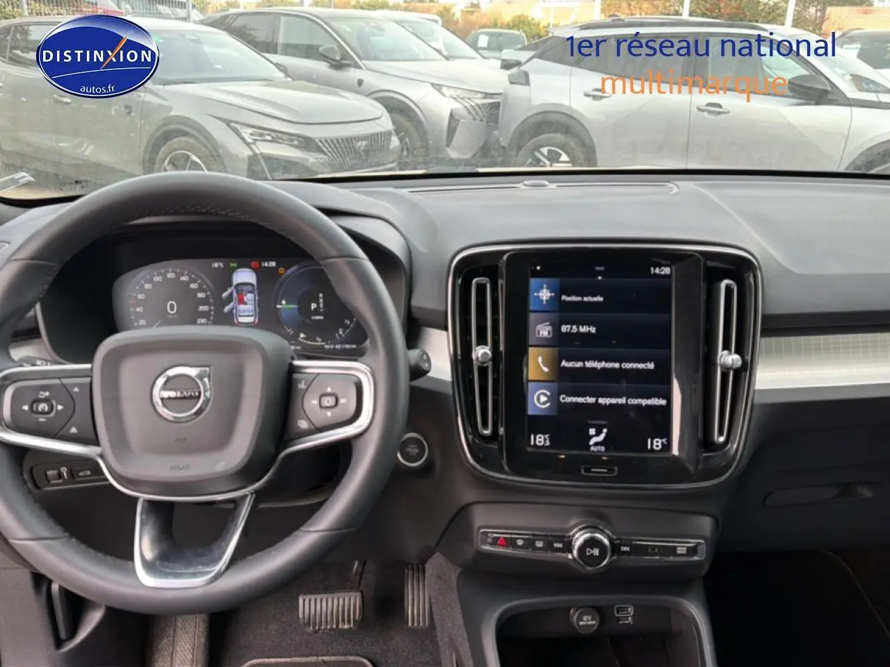 Vue intérieure frontale du tableau de bord du Volvo XC40 gris, avec volant cuir multifonction et écran tactile central.
