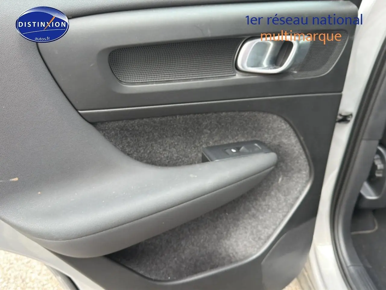 Vue rapprochée de la porte avant droite grise du Volvo XC40 T4 recharge avec accoudoir et commande de vitre.