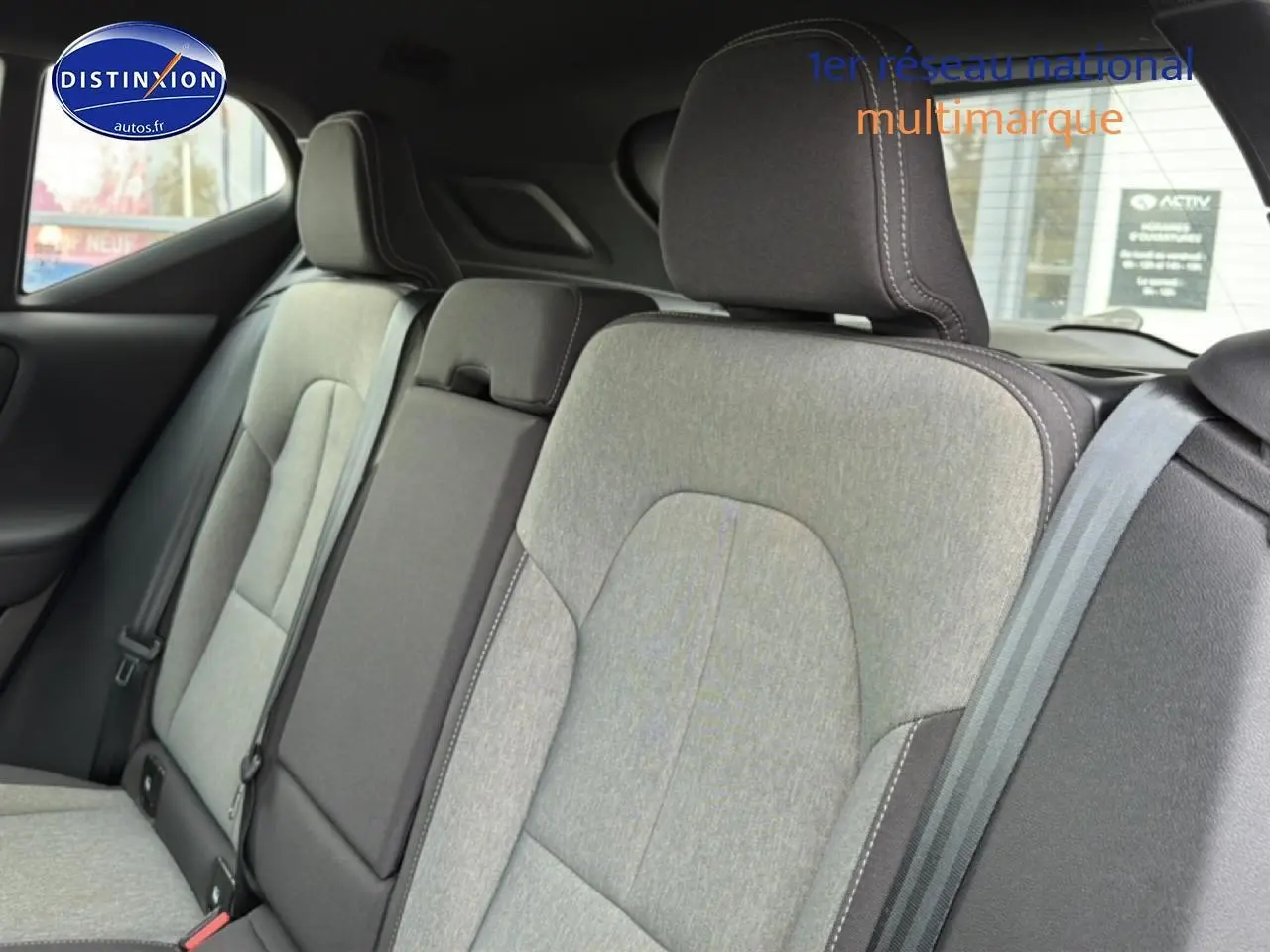 Vue intérieure sur la banquette arrière gris clair du Volvo XC40 T4 Recharge 2023 avec accoudoir central relevé.