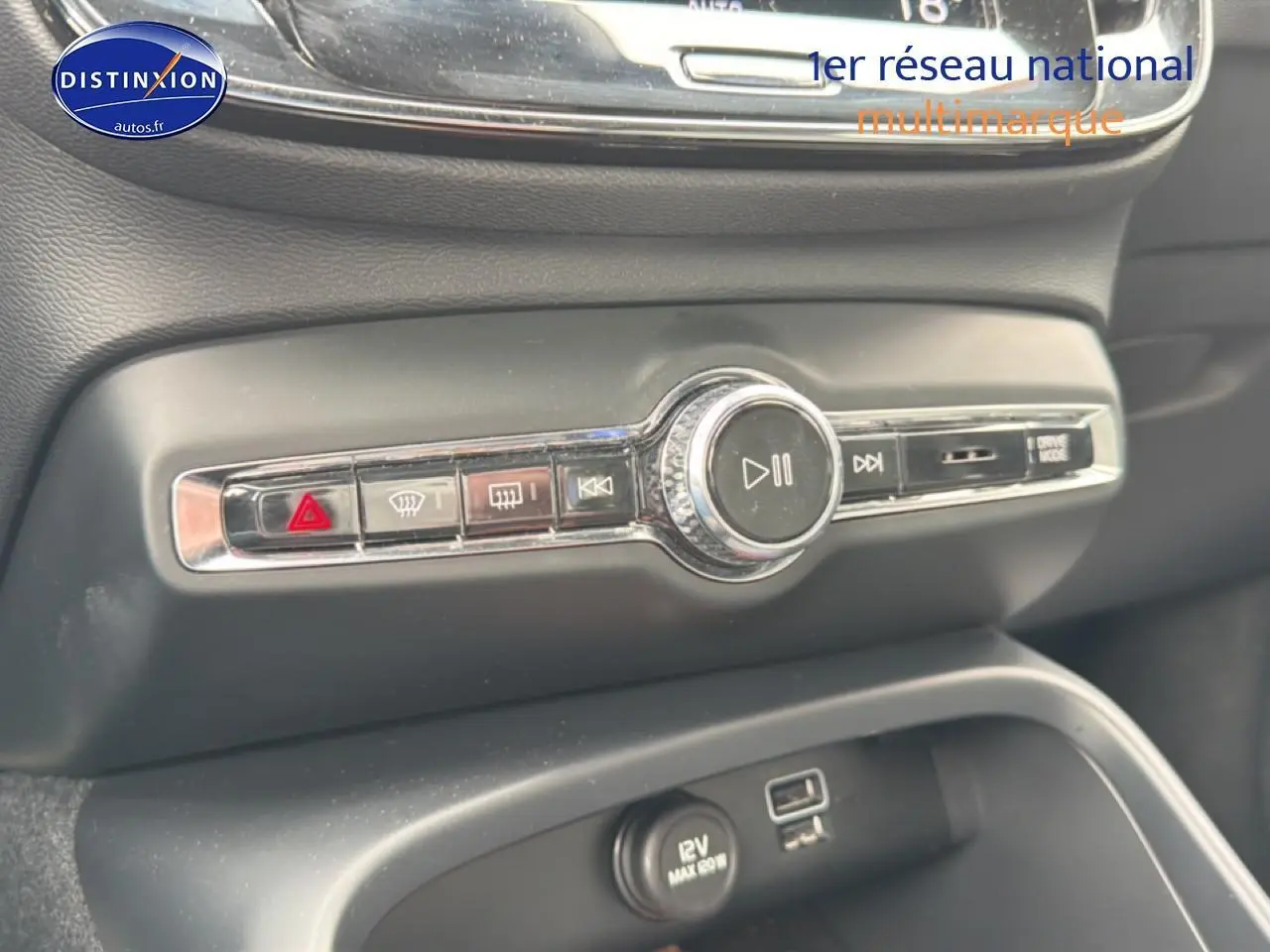 Gros plan sur la console centrale noire du Volvo XC40 T4 recharge 2023, avec commandes audio et prise 12V visible.