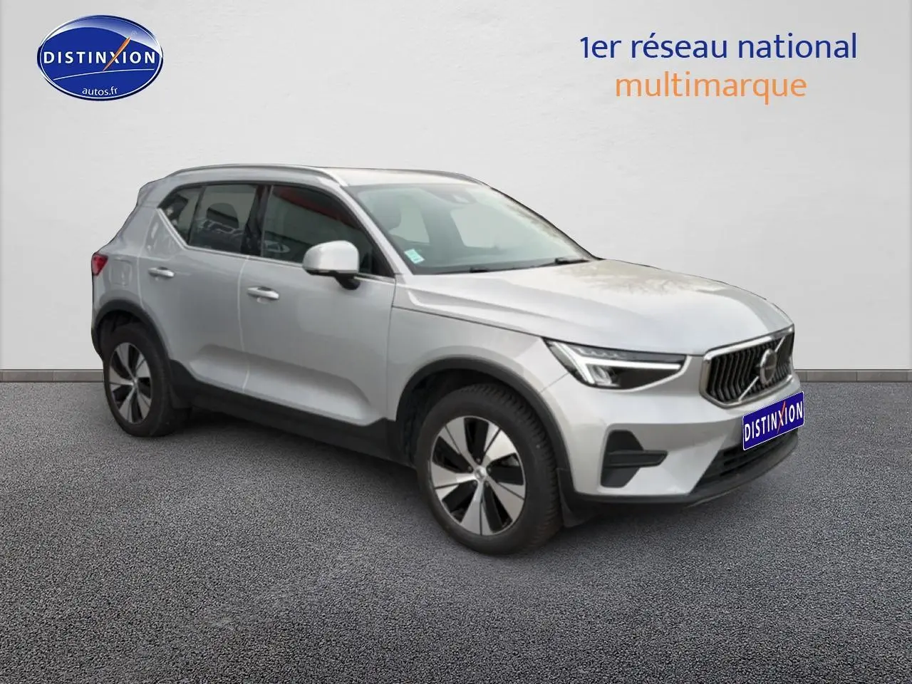 Vue 3/4 avant droit d'un Volvo XC40 T4 hybride gris avec jantes alu et calandre distinctive.