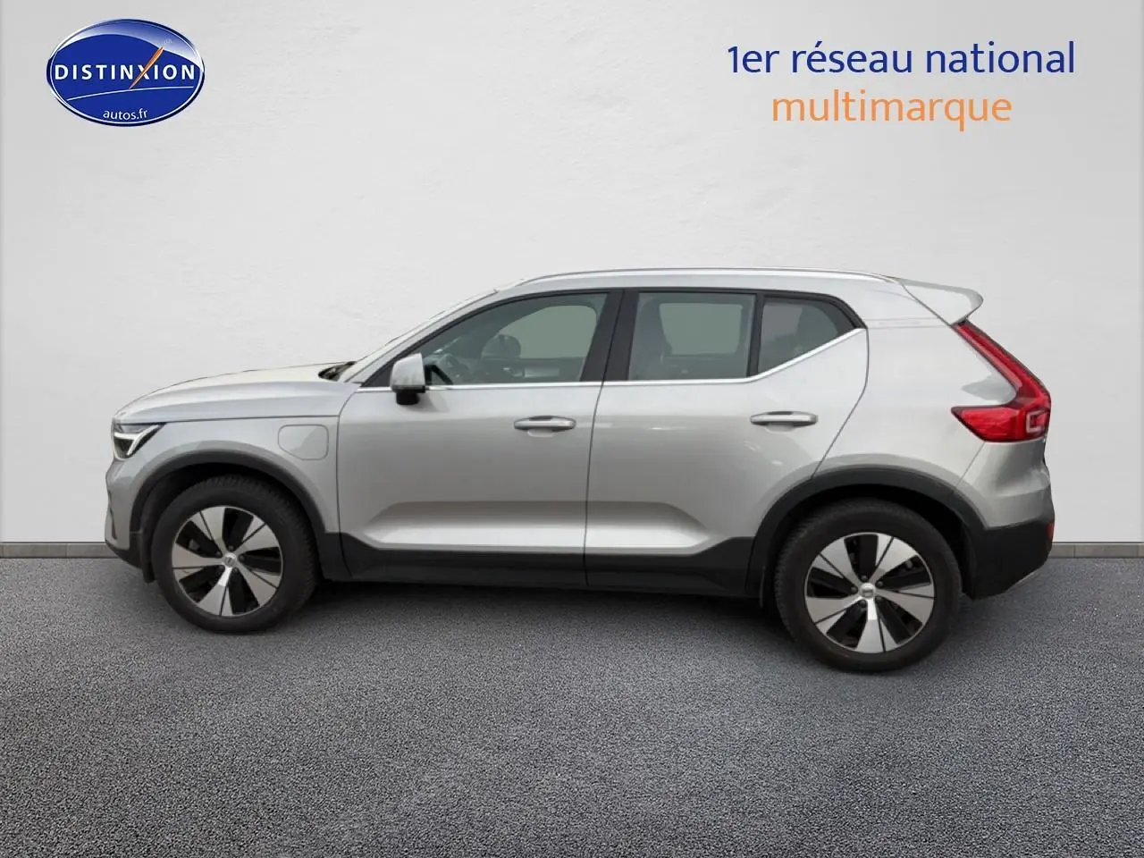 Profil côté gauche d'un Volvo XC40 T4 hybride gris 2023 avec jantes alu et becquet arrière visible.