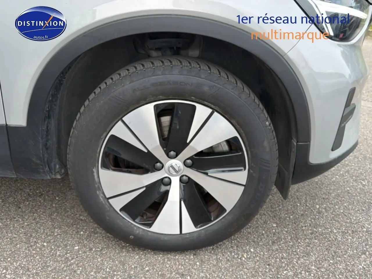 Gros plan sur la roue avant droite d’un Volvo XC40 gris 2023 avec jante alu bicolore et partie avant visible.