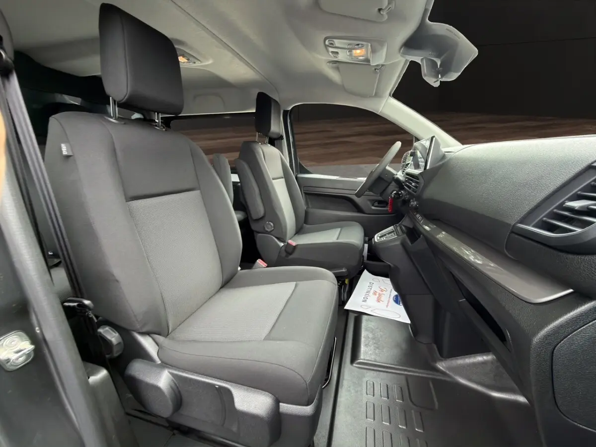 Vue intérieure côté droit du Citroën Jumpy gris foncé, montrant les sièges avant et le tableau de bord moderne.